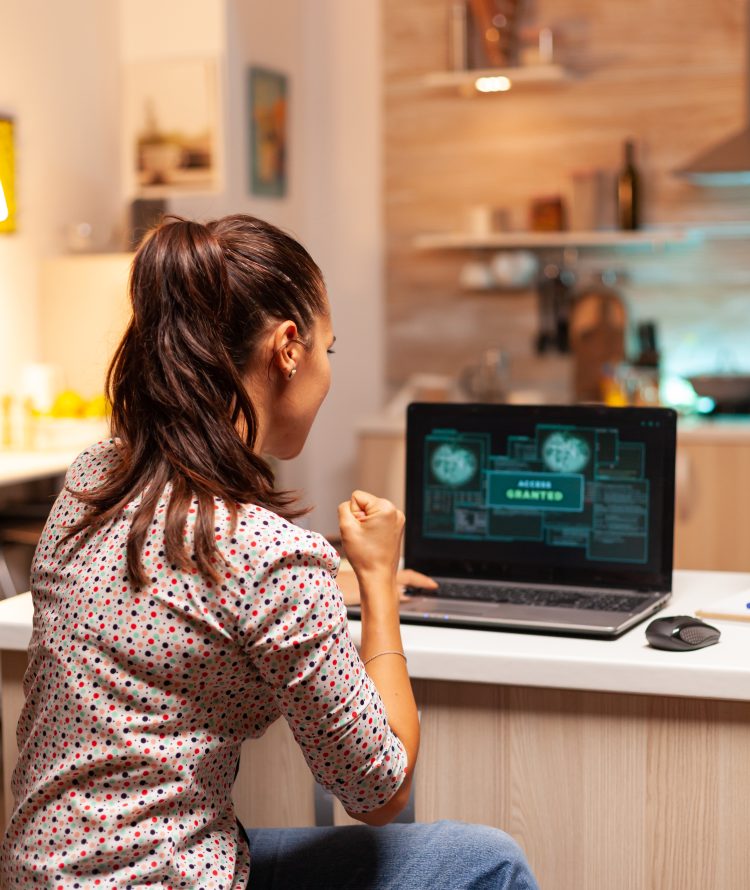 Happy woman hacker after cracking firewall of government and getting access granted. Programmer writing a dangerous malware for cyber attacks using performance laptop during midnight.